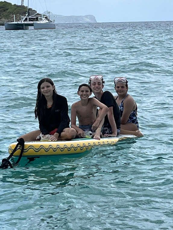 Guests enjoying calm turquoise water and floating near Peter Island during a private catamaran charter in the British Virgin Islands aboard Aquanimity