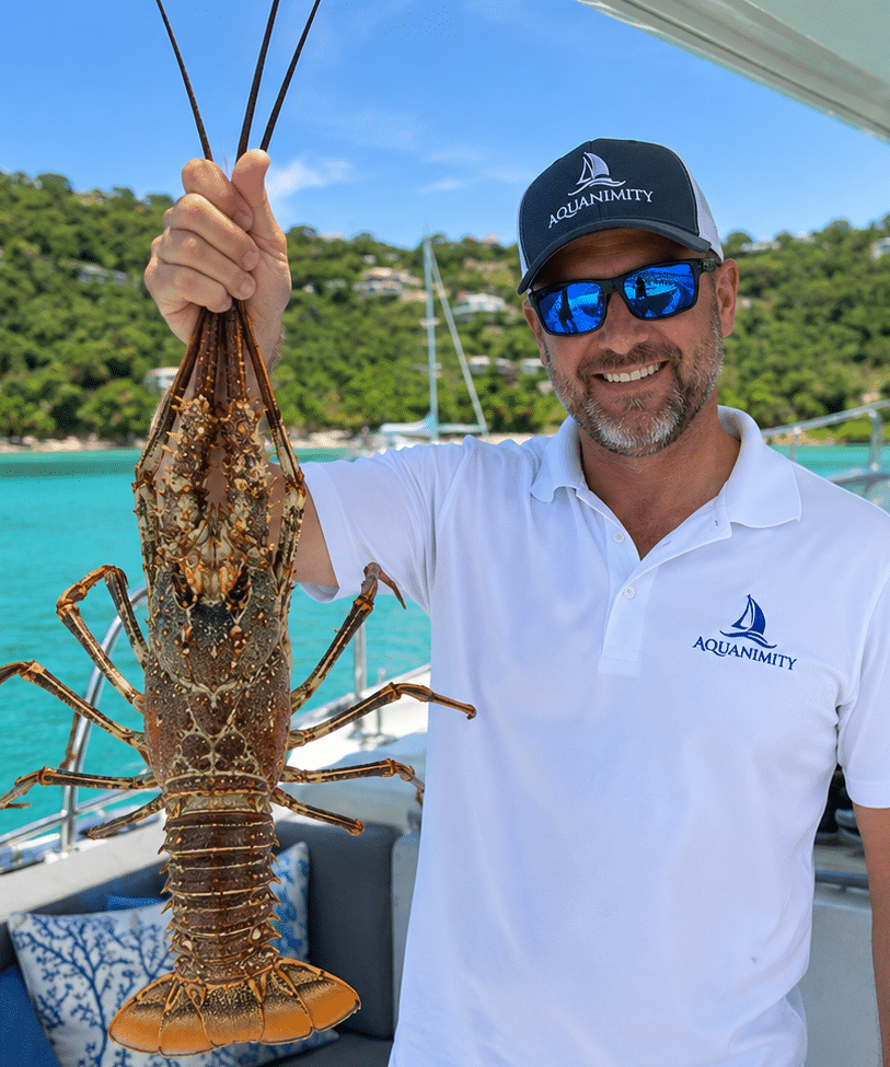 Crew holding fresh lobster aboard Aquanimity private yacht charter