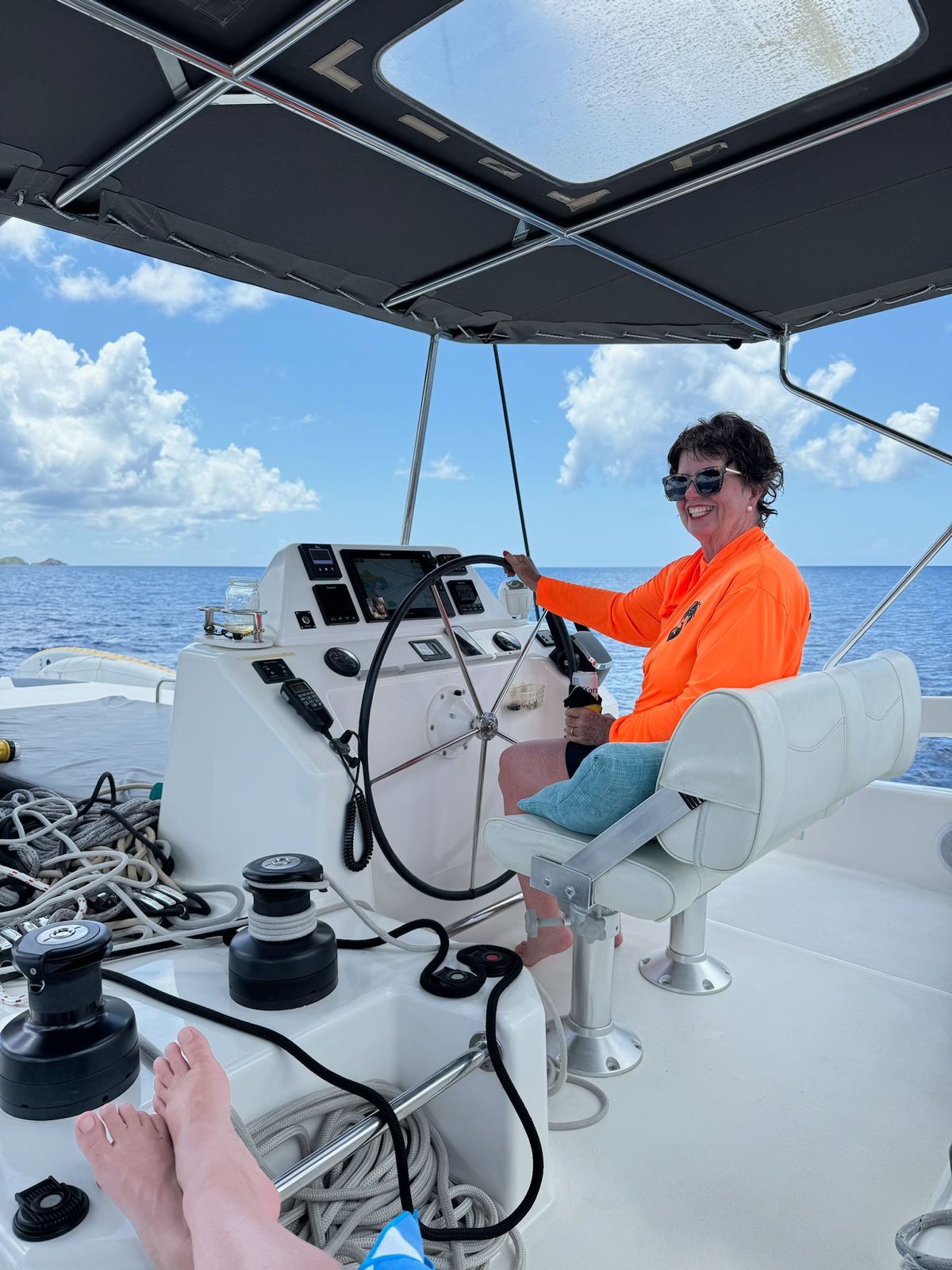 Guest at the helm aboard Aquanimity during a BVI yacht charter near Virgin Gorda